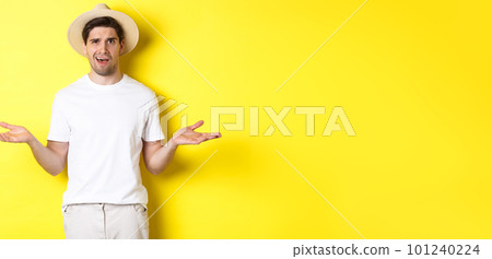 Concept of tourism and summer. Confused guy traveller shrugging, cant understand something, standing against yellow background 101240224