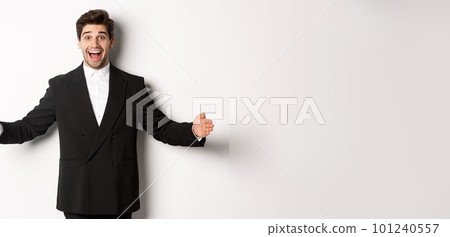 Portrait of excited handsome man in suit, shaping big object on copy space and smiling amazed, holding something, standing over white background Portrait of excited handsome man in suit, shaping big object on copy space and smiling amazed, holding something, standing over white background 101240557