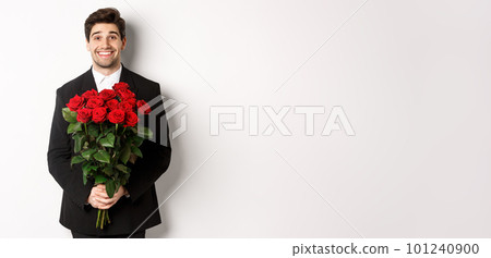 Image of handsome man in black suit, holding bouquet of roses and smiling, standing against white background Image of handsome man in black suit, holding bouquet of roses and smiling, standing against white background 101240900