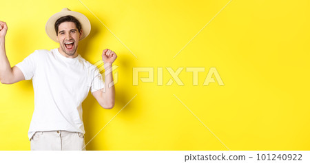 Concept of tourism and lifestyle. Happy man tourist celebrating, rejoicing over vacation, standing over yellow background 101240922