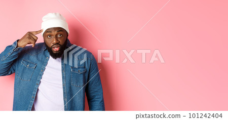 Annoyed and pissed-off african-american man pointing finger at head, scolding someone stupid, staring bothered at camera, pink background 101242404