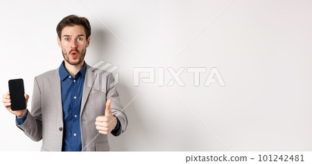 E-commerce and online shopping concept. Excited businessman recommend finance app, showing empty smartphone screen and thumb up, white background E-commerce and online shopping concept. Excited businessman recommend finance app, showing empty smartphone screen and thumb up, white background 101242481