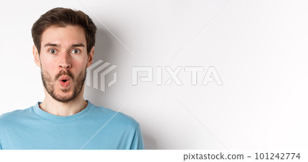 Close-up of surprised man face, saying wow and staring at camera amazed, standing on white background Close-up of surprised man face, saying wow and staring at camera amazed, standing on white background 101242774