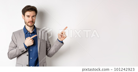 Confident handsome man in business suit pointing at upper right corner logo, showing company banner and smiling assertive, standing on white background Confident handsome man in business suit pointing at upper right corner logo, showing company banner and smiling assertive, standing on white background 101242923