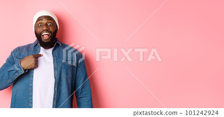 Surprised Black man in hipster beanie pointing at himself, staring at camera amazed, standing over pink background Surprised Black man in hipster beanie pointing at himself, staring at camera amazed, standing over pink background 101242924