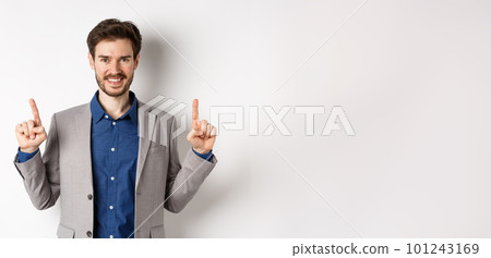 Confident successful businessman pointing fingers up, smiling and showing company logo, standing in suit on white background Confident successful businessman pointing fingers up, smiling and showing company logo, standing in suit on white background 101243169