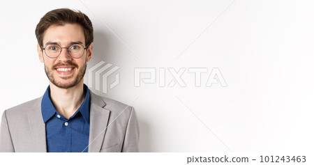 Close-up of handsome young office worker in glasses and suit smiling at camera, looking happy on white background 101243463