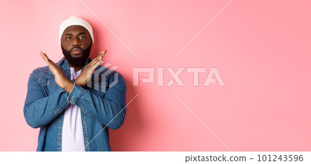 Serious african-american man saying no, showing cross to stop something bad, prohibit action, standing over pink background Serious african-american man saying no, showing cross to stop something bad, prohibit action, standing over pink background 101243596