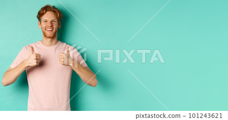 Cheerful bearded man with red hair showing thumbs-up, like and approve something, praising promo, standing against turquoise background Cheerful bearded man with red hair showing thumbs-up, like and approve something, praising promo, standing against turquoise background 101243621