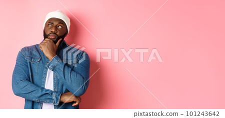 Serious thoughtful african american male model making decision, thinking and staring at upper left corner, choosing or pondering, standing over pink background Serious thoughtful african american male model making decision, thinking and staring at upper left corner, choosing or pondering, standing over pink background 101243642