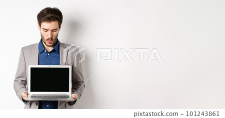 Handsome caucasian businessman in suit showing empty laptop screen, demonstrate promo, standing on white background 101243861
