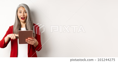 Business. Surprised female senior employer pointing at digital tablet screen, staring amazed at camera, checking out online promotion, white background 101244275