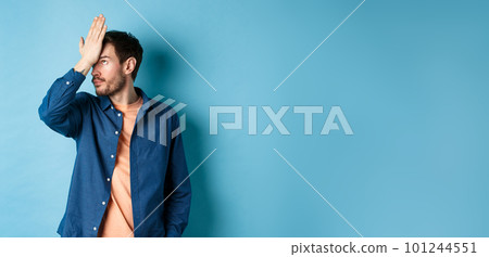 Annoyed and tired man facepalm, roll eyes and look bothered by stupid behavior, standing on blue background Annoyed and tired man facepalm, roll eyes and look bothered by stupid behavior, standing on blue background 101244551