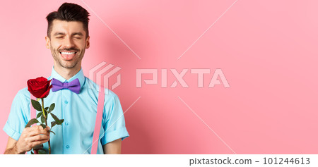 Happy man showing tongue and smiling, holding red rose for girlfriend on Valentines day, enjoying romantic date, pink background 101244613