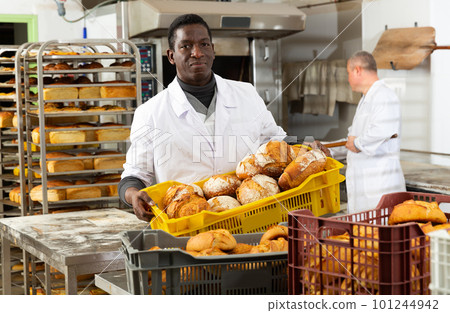 African bakery worker carrying box with loaves 101244942