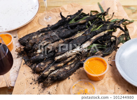 On wooden table covered with paper, fried Catalan green onion kalsot and two small balls of sauce On wooden table covered with paper, fried Catalan green onion kalsot and two small balls of sauce 101244980