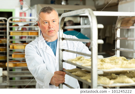 Baker pushing trolley with baked bread 101245222