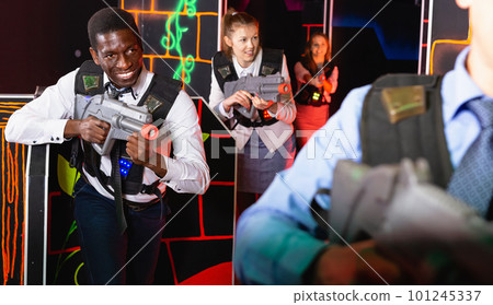 Men and women in business suits playing laser tag emotionally in dark room Men and women in business suits playing laser tag emotionally in dark room 101245337