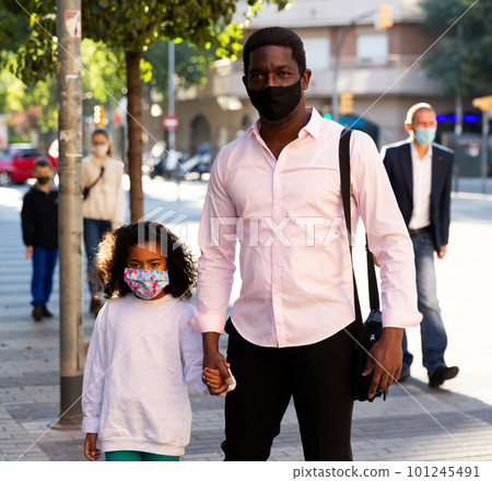 African american man in protective mask walking with preteen daughter African american man in protective mask walking with preteen daughter 101245491