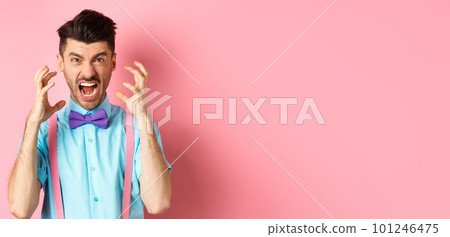 Frustrated young man losing temper, screaming and looking angry at camera, shaking hands pissed-off, standing mad on pink background Frustrated young man losing temper, screaming and looking angry at camera, shaking hands pissed-off, standing mad on pink background 101246475