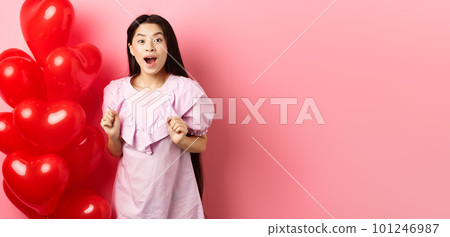 Excited and surprised teenage korean girl open mouth amazed, receive surprise gift on valentines day, looking wondered, standing near heart balloons, pink background Excited and surprised teenage korean girl open mouth amazed, receive surprise gift on valentines day, looking wondered, standing near heart balloons, pink background 101246987