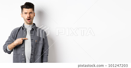 Offended young man being accused, frowning and pointing at himself shocked, standing on white background Offended young man being accused, frowning and pointing at himself shocked, standing on white background 101247203