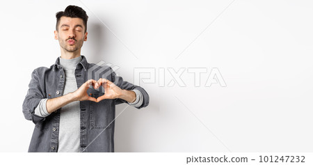 Cute young man waiting for kiss and showing heart gesture, confess on Valentines day, I love you sign, standing against white background Cute young man waiting for kiss and showing heart gesture, confess on Valentines day, I love you sign, standing against white background 101247232