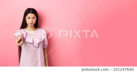 She says no. Serious asian girl shaking finger in stop gesture, prohibit and disagree with person, scolding bad behaviour, standing against pink background She says no. Serious asian girl shaking finger in stop gesture, prohibit and disagree with person, scolding bad behaviour, standing against pink background 101247680