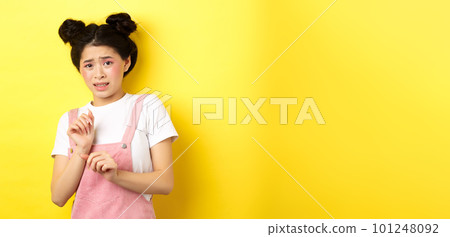 Stay away. Reluctant timid asian girl step back, raising hands to block something disgusting, grimacing displeased, say no, rejecting with aversion, yellow background 101248092