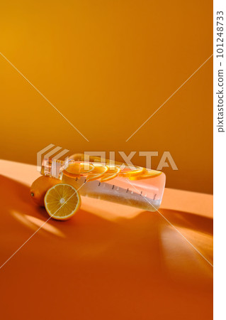 Glass water bottle with lemon on orange background. Glass water bottle with lemon on orange background. 101248733