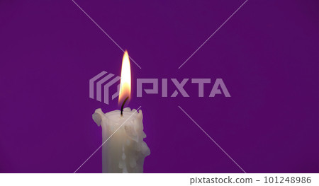Burning wax candle against a purple background 101248986