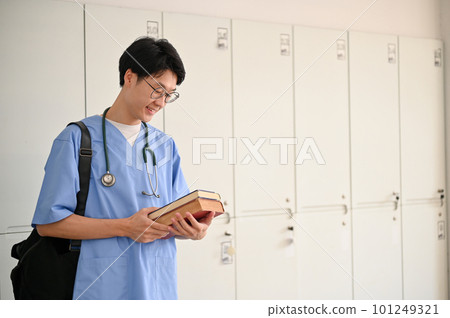 Smart young Asian male medical student in a uniform with medical books and backpack Smart young Asian male medical student in a uniform with medical books and backpack 101249321
