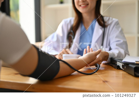 Close-up image of an Asian female doctor checking patient's pulse with a monitor 101249327