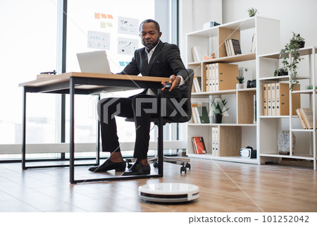 Entrepreneur switching on robot vacuum cleaner at work Entrepreneur switching on robot vacuum cleaner at work 101252042
