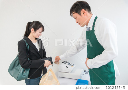 A woman shopping at a convenience store/supermarket and a male clerk reading/scanning a credit card on a terminal 101252545