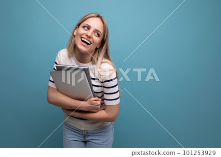 confident young woman student with a laptop in her hands on a blue isolated background with copy 101253929