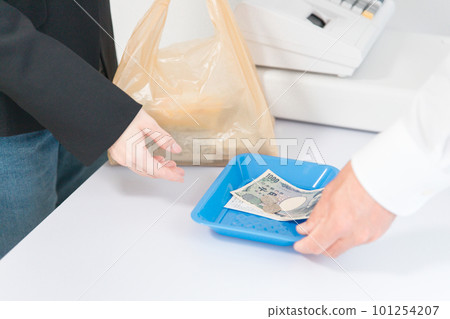 將紙幣、硬幣和零錢收據放在托盤上交給顧客的店員的手 將紙幣、硬幣和零錢收據放在托盤上交給顧客的店員的手 101254207