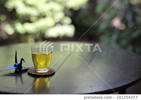 一杯茶和一隻摺紙鶴放在桌子上,在涼爽的門廊裡,背景是日本風景 一杯茶和一隻摺紙鶴放在桌子上,在涼爽的門廊裡,背景是日本風景 101254357