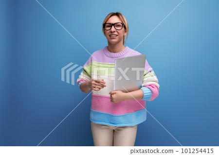 photo of cute smart blond female freelancer in striped sweater with laptop on blue background with 101254415