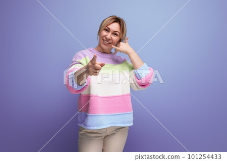 bright joyful energetic blond woman in a casual striped sweater shows her hand at the camera on a bright joyful energetic blond woman in a casual striped sweater shows her hand at the camera on a 101254433