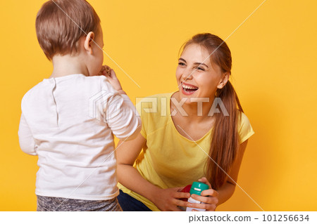 Laughing joyful woman plays with her little cute daughter, spends free time together on the weekends. A young woman is happy to bring up and care her obedient small tiny child. Family concept. Laughing joyful woman plays with her little cute daughter, spends free time together on the weekends. A young woman is happy to bring up and care her obedient small tiny child. Family concept. 101256634