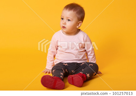 Little pretty girl sits on floor, dressed sweater, trousers with stars and red shoes, looks aside, finds friend for playing, wants on pens to mom. Copy space for your advertisment or promotion text Little pretty girl sits on floor, dressed sweater, trousers with stars and red shoes, looks aside, finds friend for playing, wants on pens to mom. Copy space for your advertisment or promotion text 101257013