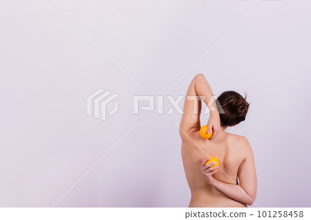 Slim woman is holding orange. Perfect female back without cellulite. 101258458