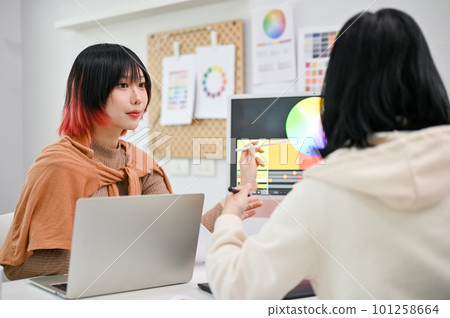 Focused Asian female graphic designer planning a new design project with her colleague 101258664