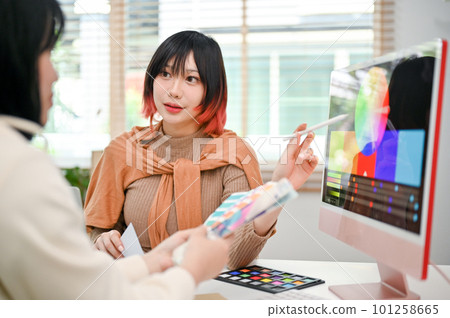 Focused Asian female graphic designer planning a new design project with her colleague 101258665
