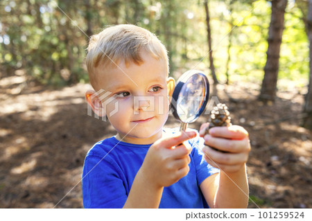 Curious boy is exploring nature with magnifying glass outdoors 101259524