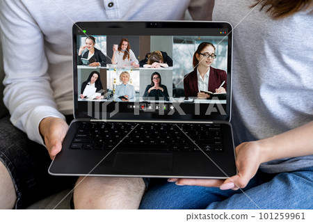 Home teleconference. Web chat. Digital cooperation. Couple holding laptop with corporate business team working online on screen. 101259961
