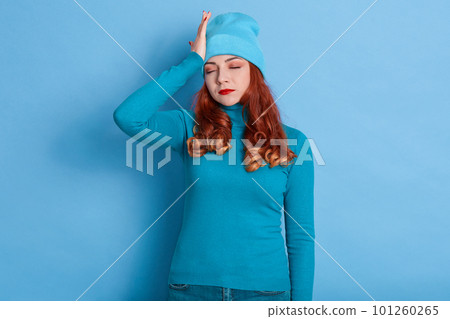 Tired sick lady with red curlers posing with closed eyes, suffering from terrible headache, wearing casual clothing, keeping hand on head, being ill, has high fever. Tired sick lady with red curlers posing with closed eyes, suffering from terrible headache, wearing casual clothing, keeping hand on head, being ill, has high fever. 101260265