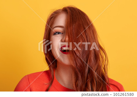 Laughing woman posing isolated over yellow background, lady expressing happiness, adorable female wearing orange shirt, girl with beautiful wavy hair. 101261580