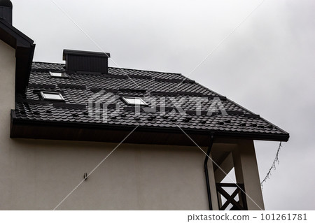 House with new brown metal tile roof and rain gutter. Metallic Guttering System, Guttering and Drainage Pipe Exterior House with new brown metal tile roof and rain gutter. Metallic Guttering System, Guttering and Drainage Pipe Exterior 101261781